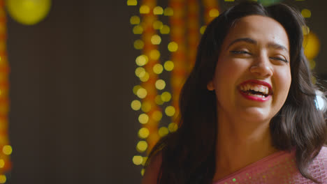Portrait-Of-Laughing-Asian-Woman-Celebrating-Diwali-Against-Bokeh-Lighting-Background